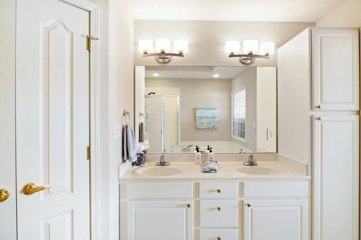 A modern bathroom with a double sink vanity, large mirror, and elegant lighting fixtures. The clean lines, fresh towels, and soft natural light create a spa-like, inviting feel.