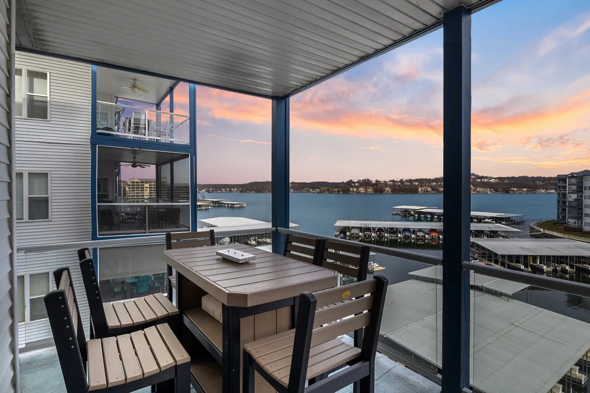An inviting outdoor dining table sits in front of a panoramic water view, with warm sunset colors filling the sky. The scene is set for al fresco dining, social gatherings, and memorable sunset celebrations.