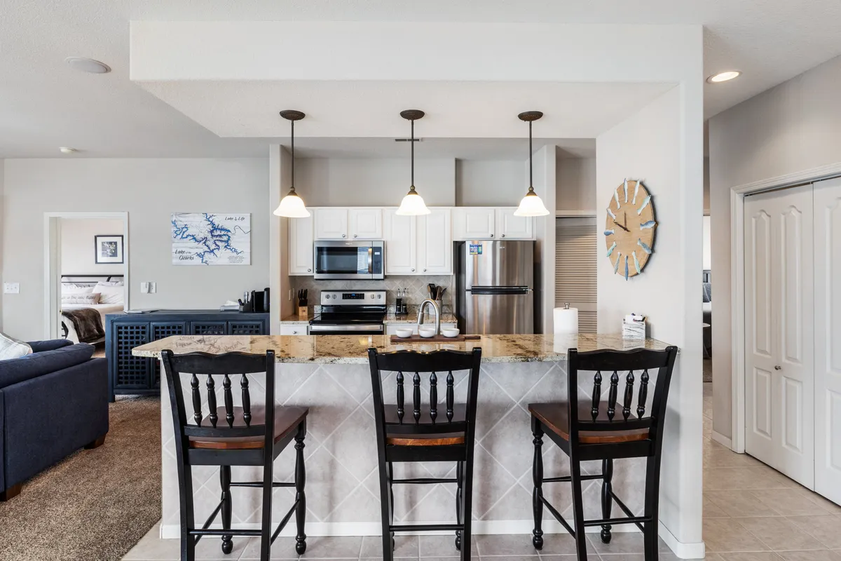 A stylish kitchen highlighted by a granite countertop, bar stools, pendant lighting, and modern appliances. The breakfast bar is the central focus, with seating that encourages casual dining or socializing while meals are prepared.